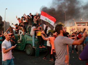 Anti-government protesters take over an armored vehicle before they burn it during a demonstration in Baghdad on October 3, 2019. (AP)