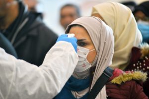 The body temperature of an Iraqi woman returning from Iran is measured upon her arrival at the Najaf International Airport on February 21, 2020, after Iran announced cases of coronavirus infections in the Islamic Republic. (AFP)
