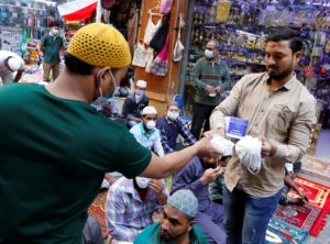 A vendor distributes protective face masks in Manama before restrictions on travel and businesses were imposed. (File photo: Reuters)