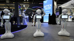Visitors stand behind robots displayed the GITEX 2020 technology summit at the Dubai World Trade center on December 8, 2020. (Photo by Karim SAHIB / AFP)