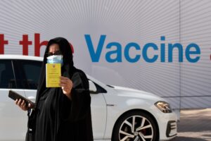 A woman displays her COVID-19 vaccine certificate in front of the Bahrain International Exhibition and Convention Center in the capital Manama, on December 24, 2020. (AFP)
