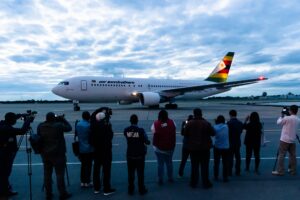Journalists take footage as an Air Zimbabwe aeroplane arrives with a donation of 200,000 doses of the Sinopharm coronavirus vaccine from China on February 15, 2021 at the Robert Mugabe International Airport. (AFP)