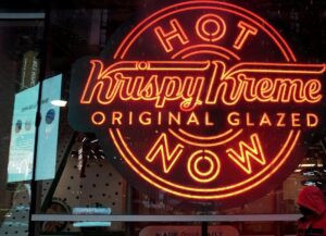 A man walks past a Krispy Kreme “Hot Now” neon sign in Times Square of New York City, Oct. 16, 2020. (Reuters)