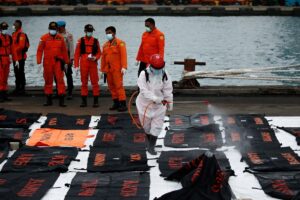 An Indonesian Red Cross worker sprays disinfectant on bags containing body parts of passengers of the Sriwijaya Air flight SJ 182, which crashed into the Java sea, at Tanjung Priok port in Jakarta, Indonesia, January 14, 2021. REUTERS