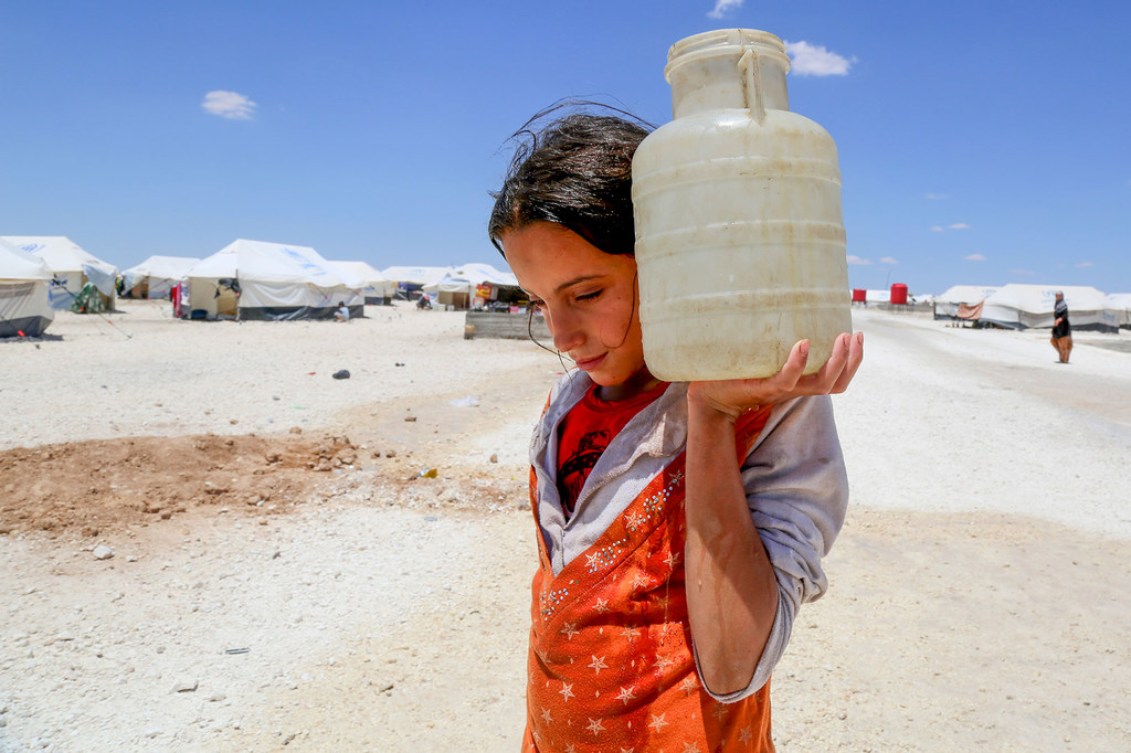 سوريا.. فتاة تحمل المياه في مخيم مؤقت في عين عيسى بسوريا/ الأمم المتحدة