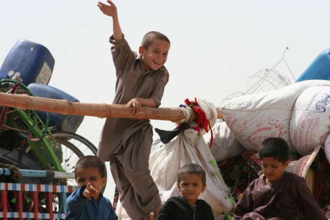 أطفال من الأفغان يلوحون بأيديهم وداعاً لباكستان وهم في طريق العودة إلى وطنهم.  © UNHCR/B.Baloch