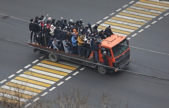 المتظاهرون يركبون شاحنة في ألماتي يوم 5 يناير. أحد الرجال يحمل عصا والآخر يحمل ما يبدو أنه درع لشرطي مكافحة الشغب. 