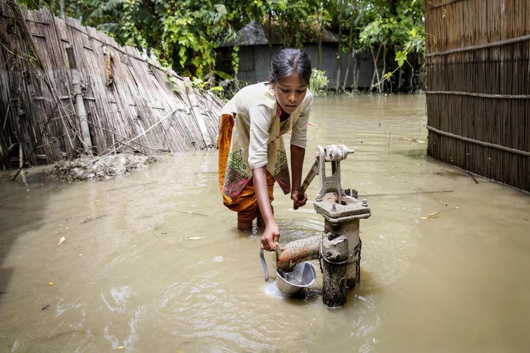 خلال فيضانات 2016 في كوريجرام، شمال بنغلاديش، تحاول فتاة ضخ المياه النظيفة من صنبور. يعد تلوث مصادر مياه الشرب خطراً كبيراً عند وقوع فيضانات.